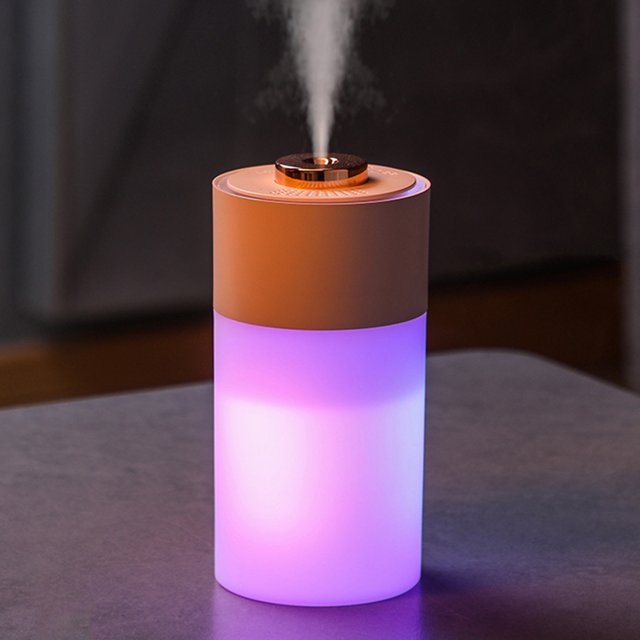 UsRHHA Essential Oil Diffuser 300ml Aromatherapy Humidifier with adjustable mist mode and 7 color LED lights. The cylindrical diffuser features a sleek design with a glowing LED light in a gradient of purple and pink hues. It emits a fine mist from the top, suitable for bedrooms, offices, or home use. Made from BPA-free ABS material, it operates quietly and is powered via USB.
