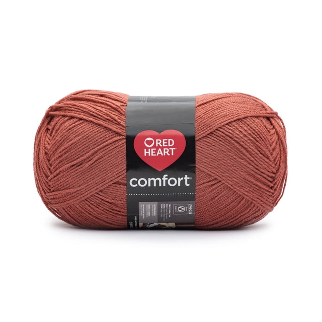 Red Heart® Comfort® Yarn, Solid, Acrylic #4 Medium, 16oz/454g, 867 Yards in rust colour, showing a tightly wound skein with a black label featuring the Red Heart logo and product details. This worsted weight yarn is machine washable and ideal for throws, blankets, knitting, and crochet projects.