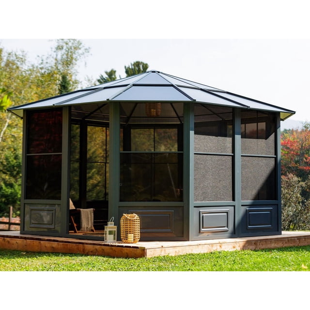 Gazebo Penguin Florence Solarium 12 Pi x 15 Pi en Ardoise, un Solarium hexagonal d'Extérieur avec un Cadre en Aluminium Enduit de Poudre et des Panneaux de Toit en polycarbonate Renforcés de 8 mm, Doté de Fenêtres Coulissantes en PVC avec Moustiquaires Intégrées et de Deux Portes Coulissantes, Installé sur une Terrasse en Bois avec Gazon Vert et Arbres, Convient Aussi comme Enceinte de spa Abritée.