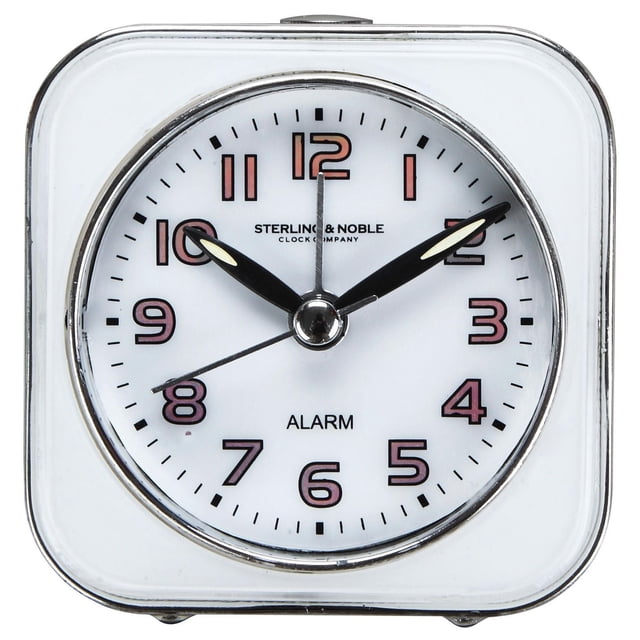 Hometrends Analog Square Alarm Clock with a white square frame and round face, black luminous hour and minute hands, thin black second hand, and pink outlined Arabic numerals. It includes an alarm with snooze and touch-activated light, suitable for bedside or travel use.