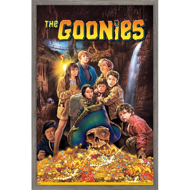 The Goonies - One Sheet Wall Poster, 22.375" x 34" depicting a group of children gathered around a pirate skull wearing a blue tricorn hat with a jeweled eye patch, atop a glowing treasure pile of gold coins, pearls, and jewels inside a cave with a waterfall and rope bridge in the background, printed on glossy poster paper ideal for framing or wall display.