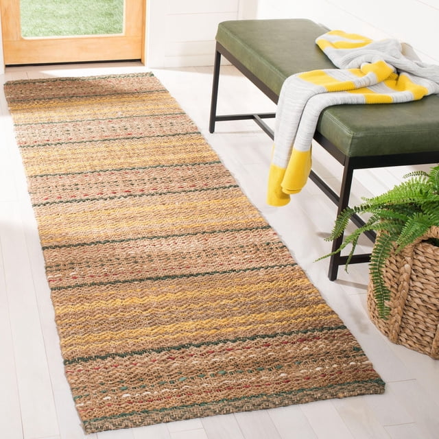 Safavieh Natural Fiber Ombre Striped Area Rug, a durable sisal and jute runner with natural beige, yellow, green, and red horizontal stripes, placed on light hardwood floor in a hallway. Positioned beside a green bench with a gray and yellow throw, and a woven basket planter with a fern. Suitable for coastal or casual beach house style interiors.
