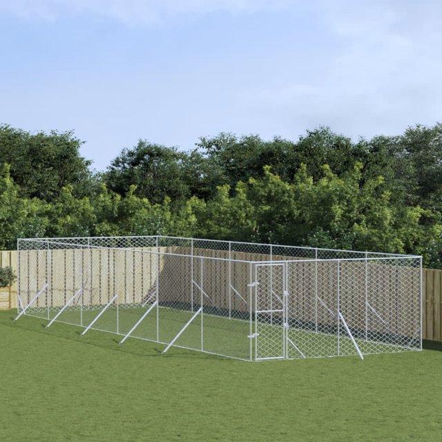 vidaXL Enclos Extérieur pour Chien Kennel Argent 4x12x2 m en Acier Galvanisé, Conçu comme un Enclos Extérieur Sécuritaire pour Animaux avec Conception en Maille, Porte Verrouillable et construction durable. Idéal pour Que les Chiens, Poules, Lapins et Autres Petits Animaux Jouent Ou Se Reposent. Positionné sur une Aire Extérieure Gazonnée avec Clôture en Bois en Arrière-Plan.