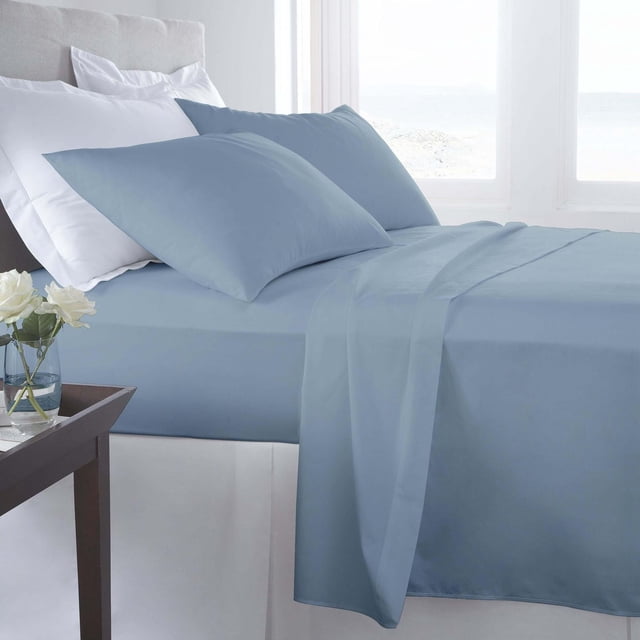 Johnson Home - 300 TC Combed Cotton Sheet Sets in blue, featuring flat and fitted sheets with extra deep pockets and pillowcases in a smooth sateen weave, displayed on a bed with beige upholstered headboard in a bright room with white curtains and a wooden side table with white roses, ideal for breathable, all-season comfort.