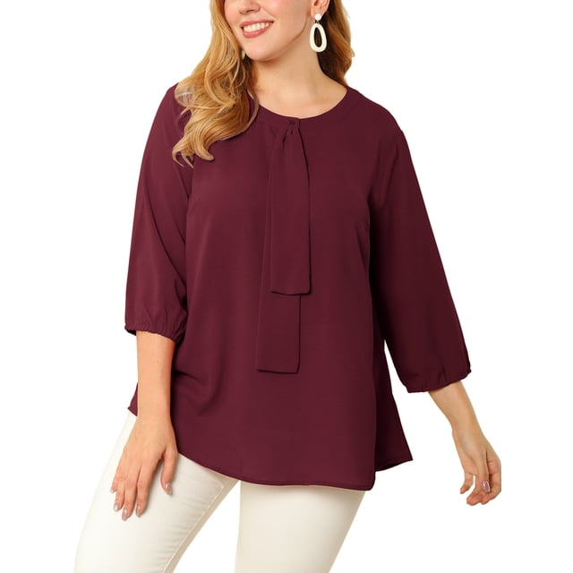 Agnes Orinda Women's Plus Size St. Patrick's Day Round Neck Tie Front Ruffle Chiffon Work Blouses in 2X Wine Red. This blouse features a round neckline, 3/4 sleeves, and a tie-front ruffle detail. Made from 100% polyester, it offers a solid wine red colour and a regular fit, designed to complement plus-size figures. Suitable for professional settings, casual outings, or festive occasions like St. Patrick's Day. Paired here with white pants for a polished look.