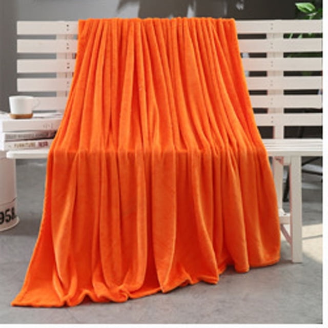 Riforla Super Soft Warm Solid Warm Micro Plush Fleece Blanket Throw Rug Sofa Bedding Blanket in vibrant orange, made of flannel material with dimensions of 70x100cm. Ideal for home decor, this throw blanket is displayed draped over a white bench in a modern indoor setting, showcasing its soft texture and rich color.