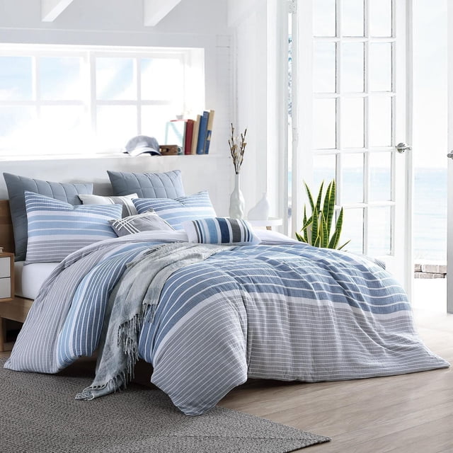 Ensemble de Housse de Couette en Coton – Collection Cordelia Comprenant une Housse de Couette 100 % Coton à Rayures Bleues et Blanches avec Taies d'Oreiller Assorties et Fermeture à Boutons, Exposée sur un Lit dans une Pièce Lumineuse avec Plancher de Bois et Vue sur l'Océan, Idéale pour Améliorer le Confort et le style de la Chambre.