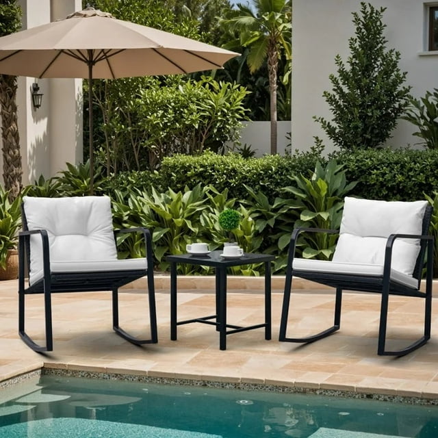 Homall 3 Pieces Outdoor Rocking Chair Furniture Sets, a modern patio furniture set with two cushioned PE rattan rocking chairs and a glass coffee table. The chairs feature black powder-coated steel frames and white polyester cushions, offering comfort and durability. The tempered glass table adds convenience for outdoor use. Perfect for patios, balconies, or poolside areas, surrounded by lush greenery.