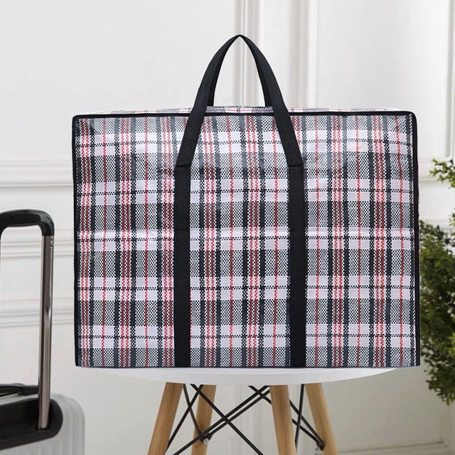 Extra Large Storage Bag Waterproof Thickened Moving Bag Folding Organizer Bag with strong handles and zippers, shown in a black and white plaid pattern with pink accents. Made of durable polyester, it measures 90x68x28cm (35.4x26.7x15in) and features reinforced handles and double-stitched seams for added strength. The bag is displayed on a wooden stool in a bright indoor setting.