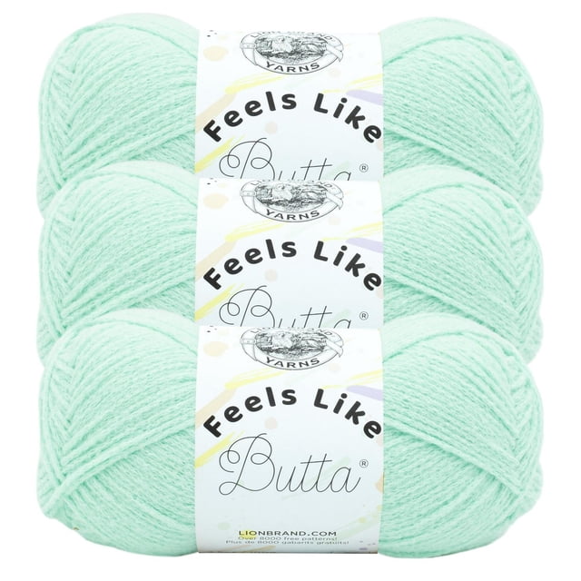 Lion Brand Feels Like Butta ® Yarn #4 Medium/Worsted Yarn 100g/199m 3-Pack in pastel mint green, three skeins stacked horizontally with white labels showing the brand logo and product name. This soft 100% polyester yarn is machine washable and ideal for knitting and crochet projects, also suitable for making wearable accessories.