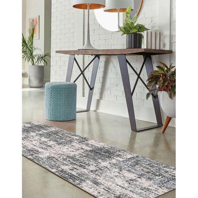 ECARPET Claudia Traditional Runner Rug in grey with a weathered Turkish geometric and tribal pattern on durable synthetic fibers, laid on a polished concrete floor in a modern room with a wooden table featuring black metal legs, a round mirror, a white lamp with copper interior, and green potted plants, ideal for high-traffic areas.