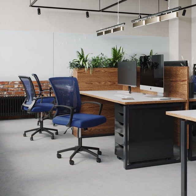 CorLiving Cooper ergonomic mesh back adjustable height adult office chair with wheels, featuring a blue padded seat and black breathable mesh back, placed in a modern office with wooden desks, computer monitors, and green plants on divider panels.