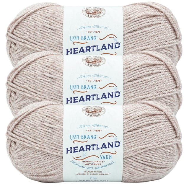 Lion Brand Yarn Heartland Yarn 3Pack with three skeins of worsted weight acrylic yarn in soft beige, featuring white labels with blue and brown text. This machine washable yarn is ideal for knitting, crochet, and crafting projects.