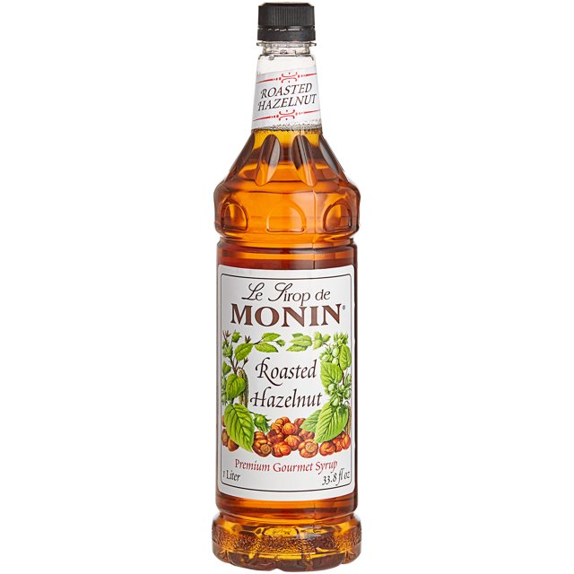 Monin Sirop Aromatisé aux Noisettes Rôties de Qualité Supérieure de 1 Litre dans une Bouteille Incassable au design Épuré. le Sirop Brun Doré Est Fait avec du Sucre de Canne Pur et Sans Arômes Artificiels, Offrant un Goût Sucré et Fumé Idéal pour Rehausser les Cafés, cocktails, desserts et Vinaigrettes. l'Étiquette Présente des illustrations de Noisettes et de Feuilles, Mettant en Valeur Ses Ingrédients Naturels.