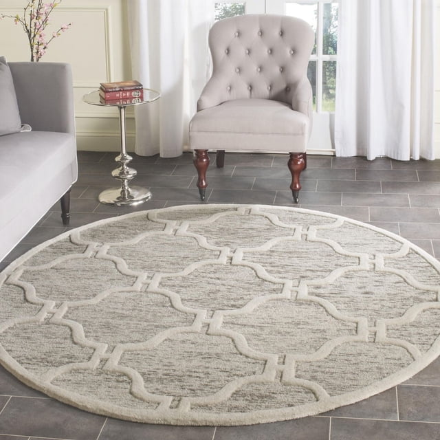 Safavieh Cambridge Kodey Tapis Géométrique Délavé de Forme Ronde avec un Motif Géométrique Texturé Délavé dans des Tons beige et Gris Neutres, Posé sur un Plancher de Carreaux Gris dans un Salon avec un Fauteuil Capitonné Gris Pâle avec des Pieds en Bois et une Petite table d'Appoint Ronde Argentée Tenant des Livres, Convient pour Ajouter un style et une texture Américains Modernes à la Déco de la Maison.