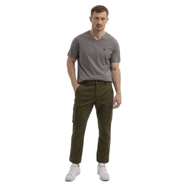 U.S. Polo Assn. Men's Slim Straight Cargo pants in olive green with mid-rise fit, featuring side cargo pockets, zippered side pockets, and a back double welt pocket, styled with a grey V-neck t-shirt and white sneakers, shown in a front-facing full-length view on a white background.