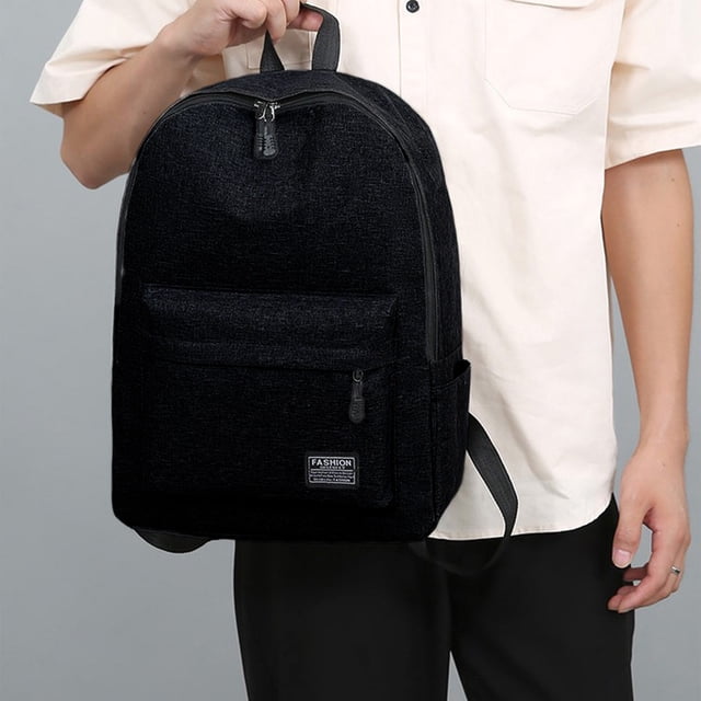 Dvkptbk Backpack Backpack Outdoor Backpack Fashion Backpack Large Capacity Backpack Student Backpack School Supplies in black color. Made of durable nylon material, it features a spacious design with compartments for organizing laptops, documents, and personal items. The ergonomic straps ensure comfortable carrying, and its water-resistant construction protects contents from rain. Shown in a lifestyle setting, held by a person wearing a light shirt and dark pants.
