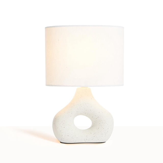 Anko Donut Table Lamp with a white fabric drum shade and speckled white ceramic donut-shaped base with hollow center, shown front-facing on a white surface, ideal for warm ambient lighting in bedrooms or living spaces.