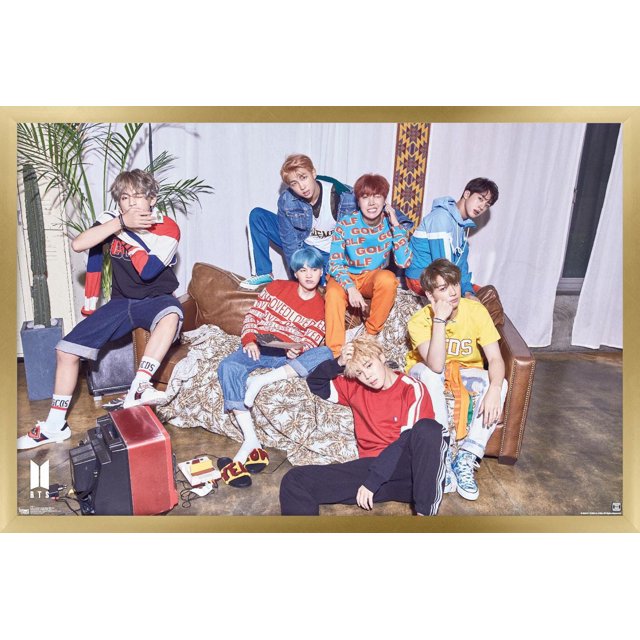 BTS - LOVE YOURSELF ? 'Her' Wall Poster, 22.375" x 34" framed showing seven members in colorful casual streetwear seated and lounging on a brown leather couch with a patterned throw, against a white curtain backdrop with a tall green plant and vintage red and black television, suitable as wall art for room decor.