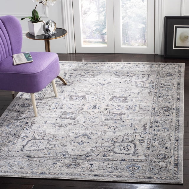 SAFAVIEH Charleston Zharko Overdyed Floral Area Rug featuring a traditional floral pattern in muted blue, grey, and cream tones, power loomed with synthetic yarns. Displayed on dark hardwood floors under a purple accent chair and side table, suitable for enhancing living or dining rooms with classic southern charm.