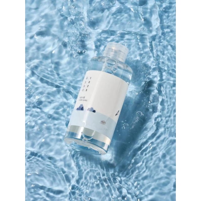 Round Lab 1025 Dokdo Toner in a clear plastic bottle with a white label featuring blue mountain graphics, floating in rippling water to emphasize its mineral-rich seawater formula that balances moisture, gently exfoliates dead skin cells, and soothes sensitive skin.
