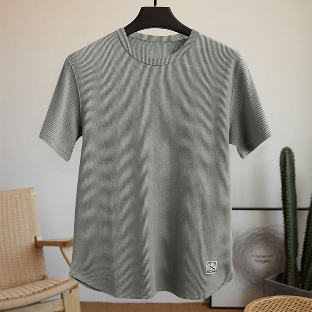 Men's solid color comfortable sport casual short-sleeved round neck shirt in grey, made of 95% polyester and 5% spandex for a breathable and lightweight feel. The shirt features a ribbed texture, short sleeves, and a round neckline, ideal for spring and summer activities such as fitness exercises or casual daily wear. Displayed on a hanger in a minimalist indoor setting with a chair and cactus in the background.
