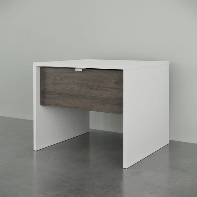 Nexera 1-Drawer Nightstand with white melamine finish and bark grey drawer front featuring a concealed metal handle, scratch, stain, and water-resistant top panel, measuring 19.75 in W x 18 in D x 16.625 in H, with open space below the drawer for airy bedroom storage.