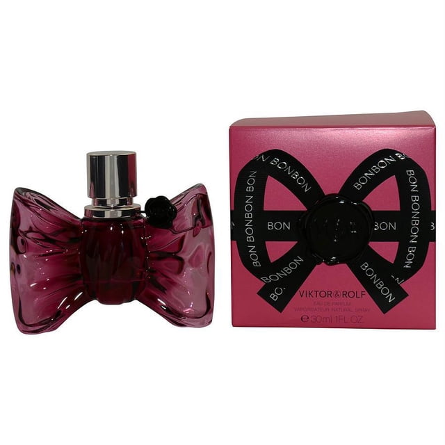 Bonbon By Viktor & Rolf Eau De Parfum Spray 1 oz for women, featuring a 1 oz bottle with a unique bow-shaped design in a deep pink hue. The fragrance includes notes of mandarin orange, orange, peach, caramel, and orange blossom. The product is displayed alongside its matching pink box with black ribbon detailing.