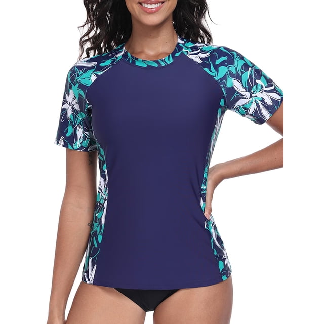 Charmo Color Blocked Swimsuit Tops for Women, a short-sleeve rash guard with UPF 50+ sun protection and quick-dry fabric. The navy blue swim shirt features floral-patterned sleeves in teal and white, ideal for women's swimwear, surfing, and outdoor activities.