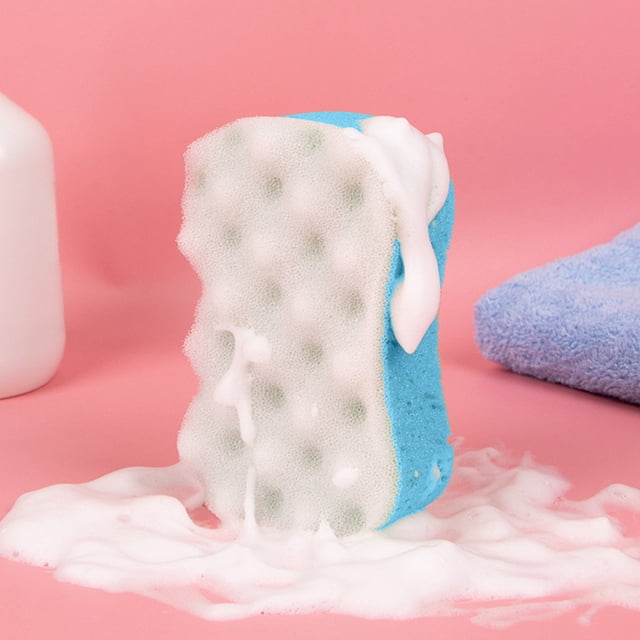 TopLLC Wave Bath Sponge in blue, featuring a dual-sided design with a textured surface for exfoliation and a soft side for sensitive skin. The sponge is shown producing abundant foam with minimal soap, highlighting its efficient foaming capability. Positioned on a pink background with a towel and bottle nearby, emphasizing its use as a bath and shower accessory.