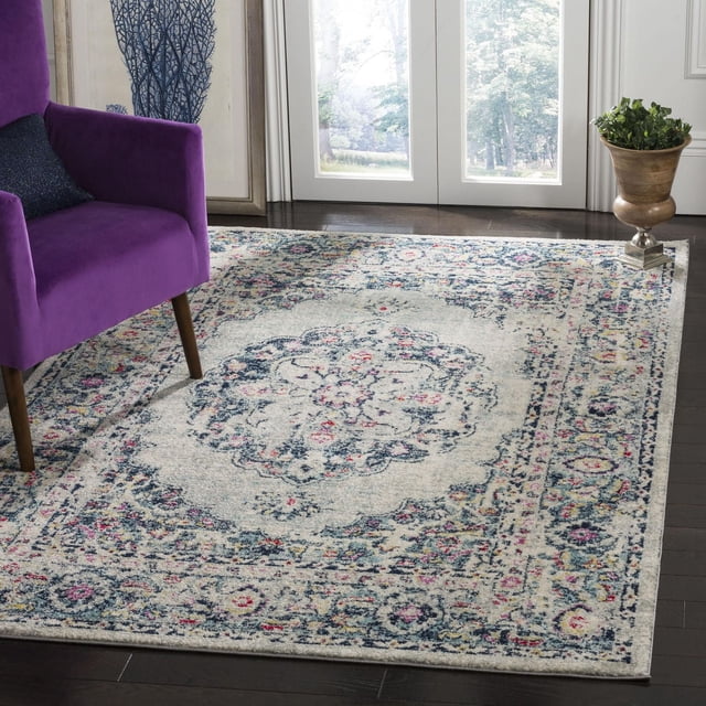 Safavieh Madison Aimee Floral Bordered Area Rug with a central floral medallion and intricate border in muted blue, pink, and cream tones, power loomed for durability, placed on dark hardwood flooring beside a purple armchair near glass doors, often used to enhance transitional home decor.