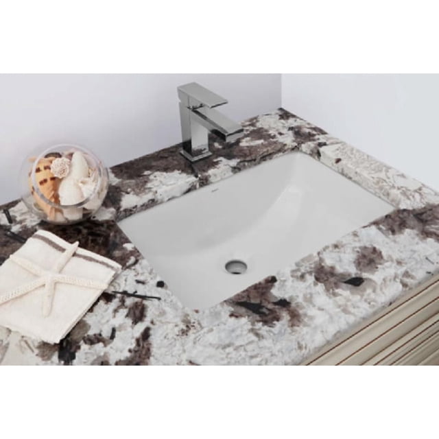 American Imaginations 23.125-in. W 15-in. D rectangle bathroom undermount sink in white color installed under a granite countertop with white, black, and brown marbling, featuring a chrome single-handle faucet, a folded white towel with a starfish accent, and a glass bowl of seashells on the left side.
