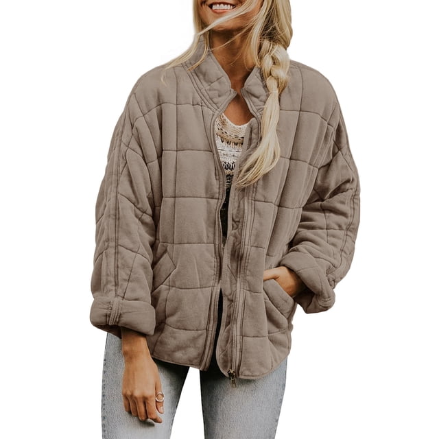 Kmbangi Women Stand Collar Long Sleeve Solid Color Full Zip Quilted Jacket in a neutral tone. This winter jacket features a padded quilted design, stand collar, long sleeves, zip closure, and pockets. Styled casually with light-wash jeans, ideal for cold weather and everyday wear.
