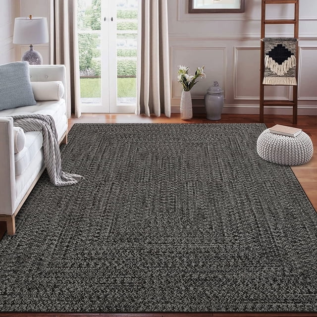 Garvee 8'x10' Area Rugs Braided Print Rug in gray brown displayed in a cozy living room setting. The rug features a braided print pattern with a low 0.23-inch pile height, crafted from durable polyester material. It includes a non-slip TPR rubber backing for stability, making it suitable for high-traffic areas like living rooms, bedrooms, and dining rooms. The rug is machine washable for easy maintenance and comes in a folding package.