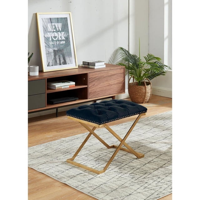 Imperial Ottoman Capitonné avec Base en X Dorée (Noir) avec un Coussin en Velours Capitonné Noir et une Garniture de Clous Décoratifs sur une Base en X Métallique Dorée, Placé sur un Tapis à Motif Gris dans un Salon Moderne avec une console Multimédia en Bois et une Plante Panier Tressée, Idéal pour des Sièges Supplémentaires Ou comme Repose-Pieds.