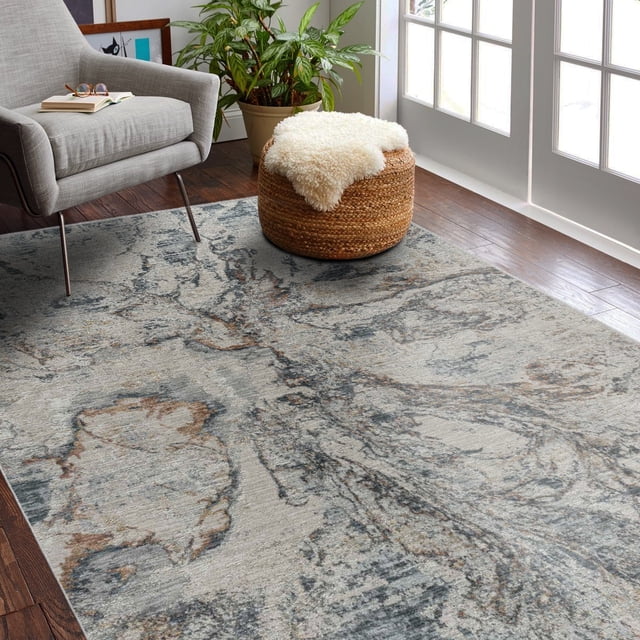 Rug Branch Melo Collection Tapis d'Intérieur Moderne Abstrait Scandinave de Forme Rectangulaire avec Motif Abstrait Atténué dans des Tons Gris, beige et Brun. Fait de 100 % polyester avec envers en jute, Posé sur un Plancher de Bois Franc Foncé à Côté d'Un Fauteuil Gris et d'Un ottoman Tissé Surmonté de Peau de Mouton Blanche, Près d'Une Fenêtre et d'Une Plante Verte. Idéal pour Salons, Salles à Manger Ou Couloirs.