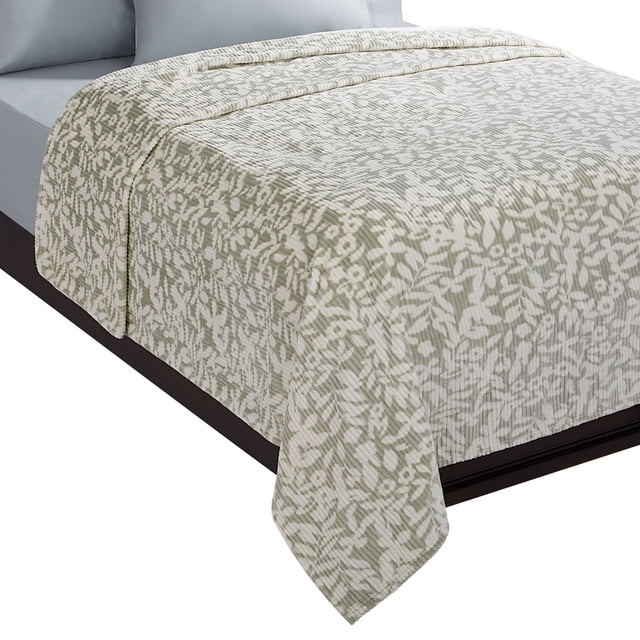 King-size bed with a light green and white floral patterned quilted bedspread featuring a ribbed texture, draped over a dark wood frame with light grey fitted sheets and pillows. This decorative bedding adds a soft, cozy layer ideal for enhancing bedroom comfort and style.