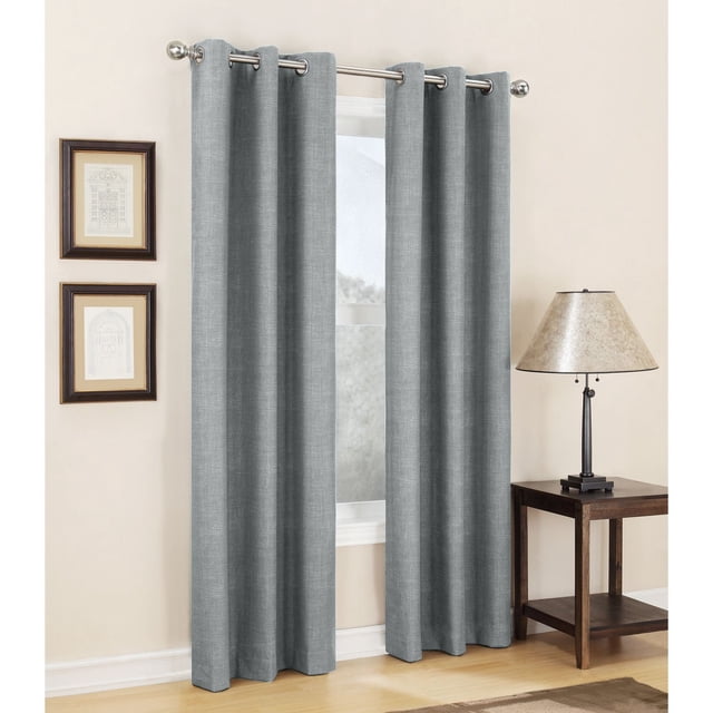 Sun Zero Carter Thermal Lined Grommet Curtain in grey with textured fabric and thermal lining for energy saving, blocking light and noise while enhancing privacy, hanging on a silver rod in a room with a wooden side table, beige lamp, and framed wall art.