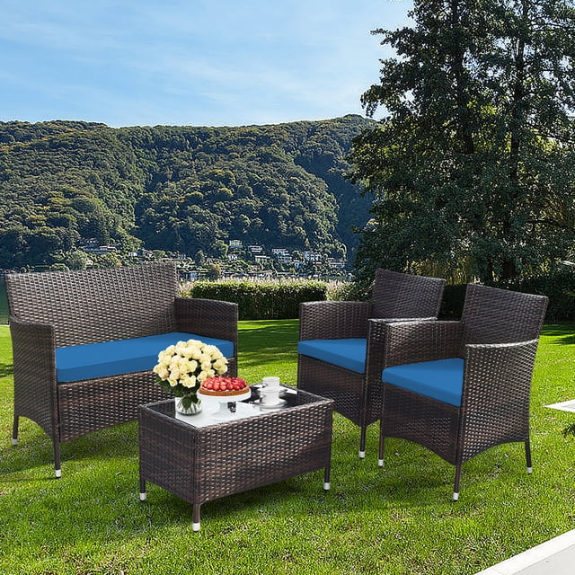 Gymax Ensemble de Conversation en Rotin pour Patio 4 Pcs pour l'Extérieur avec Coussin Bleu Paon, Incluant Deux sofas Simples, un Causeuse et une table Basse avec Verre Trempé. Fabriqué avec de l'Acier et du Rotin pour la Durabilité, l'Ensemble Comprend des Housses de Coussin Amovibles pour un Entretien Facile. Exposé dans un Jardin Extérieur Pittoresque.