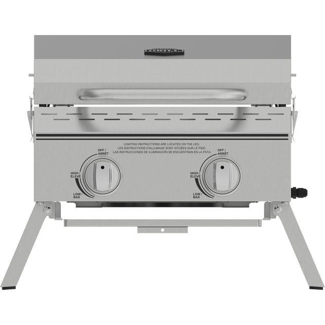Expert Grill 2 Burner Tabletop Propane Gas Grill in stainless steel with two front control knobs for off, high, and low heat settings, a locking lid handle, foldable legs for portability, and ventilation slots above the knobs, suitable for outdoor cooking and camping.