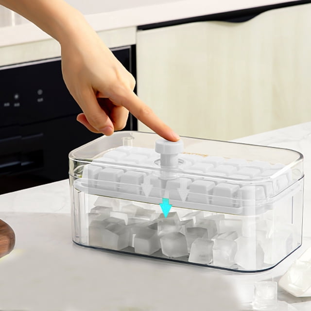 Dvkptbk Ice Trays, Ice Cubes Tray with Lid and Bin, featuring 32 ice cube molds, an ice scoop, and a press lid for easy release. The white polypropylene and ABS tray is shown in a kitchen setting, with a hand pressing the lid to release ice cubes into the transparent storage bin below. Compact and stackable design for efficient freezer storage.