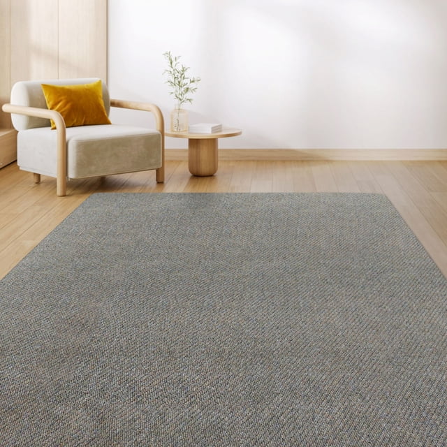 Mainstays Tapis Finley Bluestone Lavable Tufté 6'x8' sur Plancher de Bois Clair dans une Pièce Moderne avec un Fauteuil beige et un Oreiller Jaune Moutarde. le Tapis Gris Bluestone Texturé Présente une surface Tuftée Haute/basse pour Confort et Adhérence, Fabriqué à Partir de 100 % de Recyclage, Polypropylène Résistant aux Taches avec Endos TPE Écologique. Durable et Lavable à la machine, Convient aux Entrées, Cuisines, Salons Ou Bureaux.