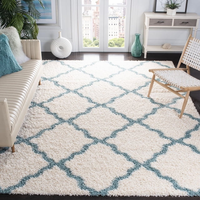 Safavieh Dallas Logan Geometric Shag Area Rug with ivory and blue Moroccan tile pattern, power-loomed polypropylene construction, and plush soft pile, shown in a bright living room with beige leather sofa, woven chair, and white console table, suitable for adding comfort and style to various home settings.