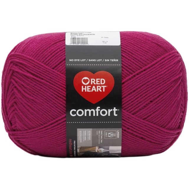 Red Heart® Comfort® Yarn, solid acrylic #4 medium weight, 16oz (454g) skein with 867 yards in shocking pink. The yarn is tightly wound with a smooth texture and a black label featuring the Red Heart logo and care instructions. Suitable for knitting and crochet projects, often used for cozy blankets and throws.