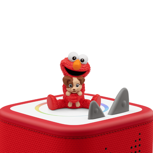 Tonies Figurine Audio Sesame Street : Elmo et Tango Mettant en Vedette une Figurine Elmo Rouge aux Grands Yeux Blancs et au Nez orange, Assise sur une Boîte Audio Rouge Recouverte de Tissu avec un Panneau Supérieur Blanc au design Circulaire Coloré et Deux Boutons de Commande Triangulaires Gris.