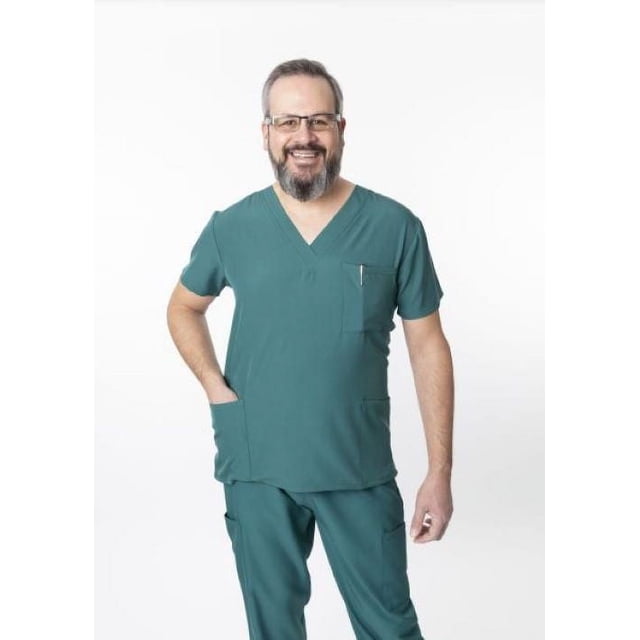Greentown Canada Scrubs 4Flex 1202 Unisex Scrub Top in teal green with an athletic fit and V-neck, shown on a front-facing model wearing matching scrub pants. The top features three pockets including a chest pocket with a pen, made from a 93% polyester and 7% spandex blend with 4-way stretch and moisture-wicking fabric for comfort and mobility.