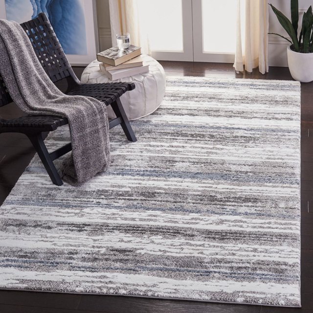 SAFAVIEH Century Tapis à Rayures Blanc Présentant un Motif Abstrait Moderne à Rayures dans des Tons Gris, Blancs et Bleus Atténués, Tissé Mécaniquement avec des Fils Synthétiques Doux pour la Durabilité et le Confort. le Tapis Se Tient sur un Plancher de Bois Franc Foncé sous une Chaise Tressée Noire avec un Jeté Tricoté Gris, à Côté d'Un pouf Blanc Surmonté de Livres et d'Un Verre d'Eau, dans une Pièce Lumineuse avec des Rideaux Crème et une Plante en Pot Verte. Convient pour Ajouter de la texture et de la Chaleur aux Espaces de Vie Contemporains.