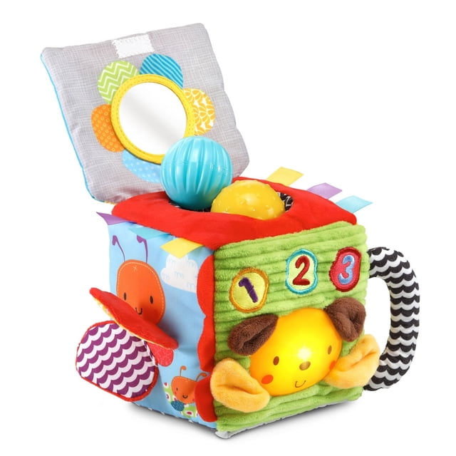 VTech Soft & Smart Sensory Cube™ - Put-and-Take Ball Play, Baby Toy - French Version, a multicolour soft fabric activity cube with six tactile sides featuring a baby-safe mirror framed by colourful petals, three textured balls in blue, yellow, and orange for put-and-take play, numbered 1, 2, 3 patches, a smiling puppy face with soft ears, and a black-and-white striped handle, designed for infant sensory learning and motor skill development.