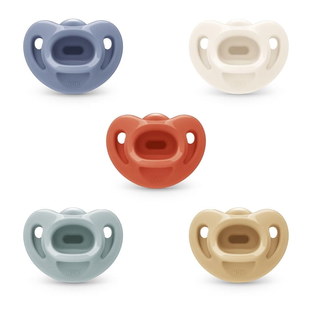 NUK Comfy Neutrals Orthodontic Pacifiers, 6-18 Months, 5 Pack, front-facing view of five BPA-free, 100% medical-grade silicone pacifiers in muted neutral colors including blue, cream, rust, light gray, and beige, each with a heart-shaped shield designed to fit under baby’s nose for easier breathing and an orthodontic nipple that supports healthy oral development.
