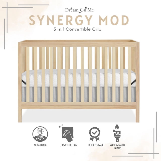 Dream On Me Synergy MOD Crib in natural New Zealand pinewood finish, front-facing view with wooden spindles and grey mattress base, a 5-in-1 convertible crib designed for nursery safety, durability, and easy cleaning.
